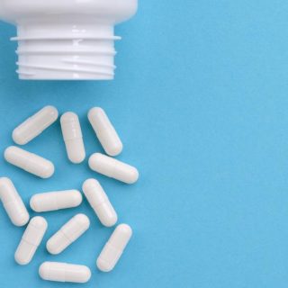 White medication capsules spilling from bottle