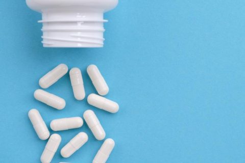 White medication capsules spilling from bottle