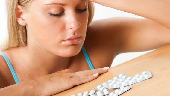 young woman looking at birth control tablets