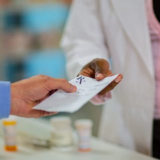 Patient handing a prescription to a pharmacist