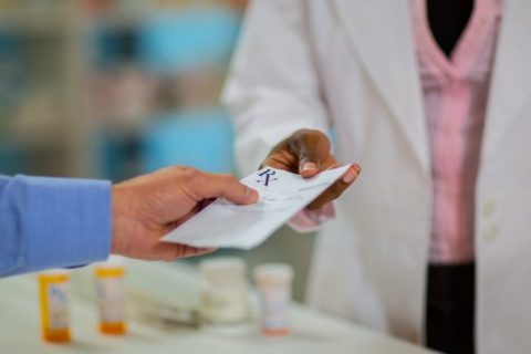 Patient handing a prescription to a pharmacist