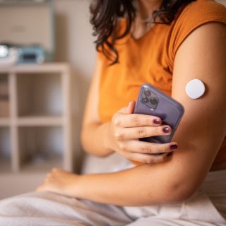 Young diabetic patient monitoring glucose level with remote sensor at home, she has a glucose monitor on her arm