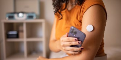 Young diabetic patient monitoring glucose level with remote sensor at home, she has a glucose monitor on her arm