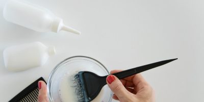 Top view of woman hand mixing hair dye color and dye hair products on white background