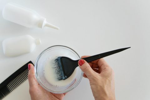 Top view of woman hand mixing hair dye color and dye hair products on white background