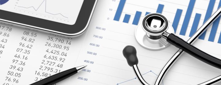 Tablet and stethoscope on table with financial statements