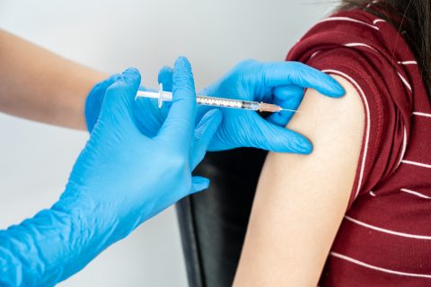 Syringe injection being placed into an arm. Provider wears blue gloves.