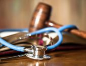 Judge's gavel and stethoscope on court room table.