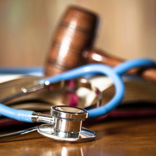 Judge's gavel and stethoscope on court room table.
