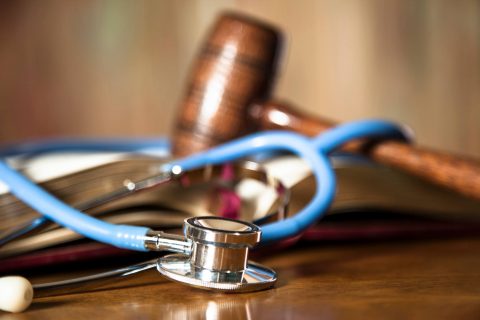 Judge's gavel and stethoscope on court room table.