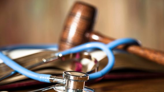 Judge's gavel and stethoscope on court room table.