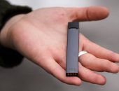 A woman is holding a Juul e-cigarette