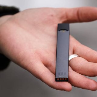 A woman is holding a Juul e-cigarette