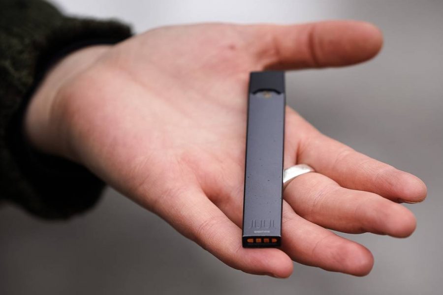 A woman is holding a Juul e-cigarette