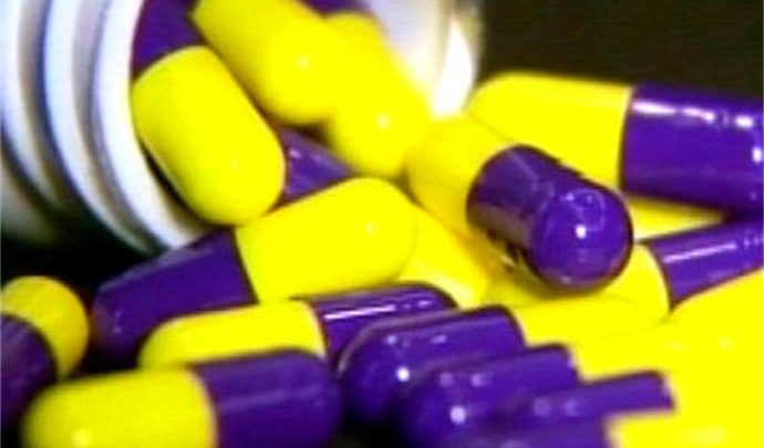 L C Image yellow and purple pills spilling out of a bottle