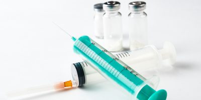 Medical syringes next to medicine bottles with ampoules.