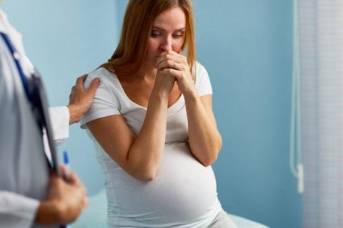 worried pregnant woman in a doctors office