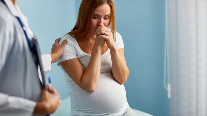 worried pregnant woman in a doctors office