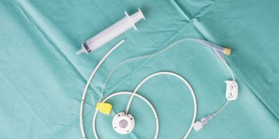 Implantable port catheter with attached tubing and access syringe on a surgical drape