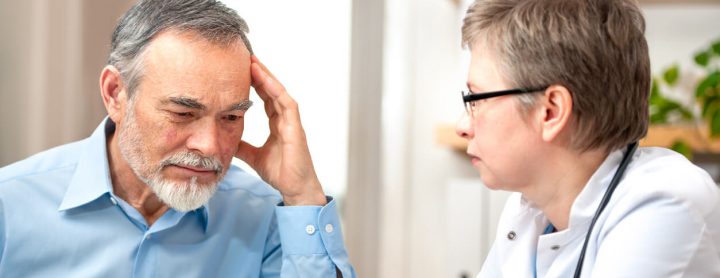Doctor discussing chronic pain with man that has headache
