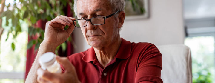 Elderly man reading his prescription pill label
