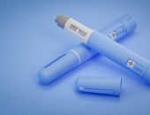 Blue semaglutide injection pens on blue background, one with cap removed showing needle.