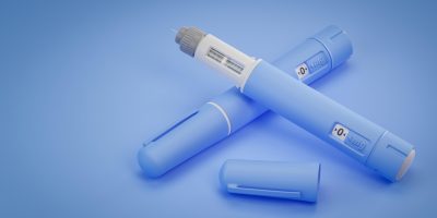Blue semaglutide injection pens on blue background, one with cap removed showing needle.