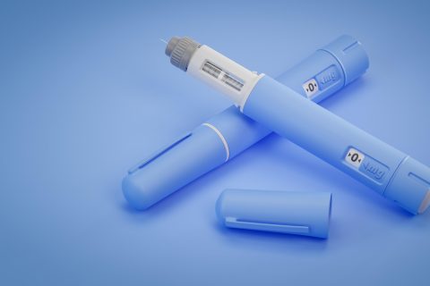 Blue semaglutide injection pens on blue background, one with cap removed showing needle.