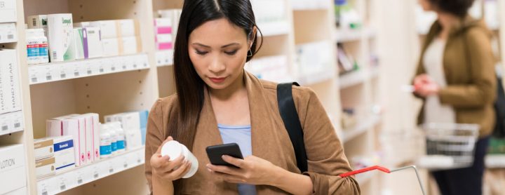 Woman in drugstore reading label on pill bottle