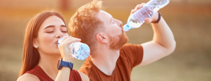 Woman and man drinking water on a run