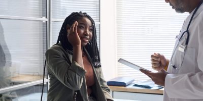 Woman with headache discussing with doctor