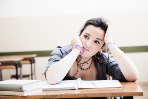 Teen mentally tired leaning over book