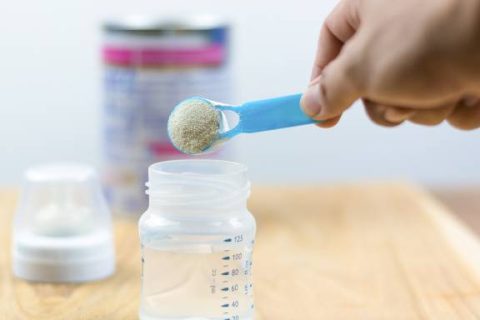 Baby formula being scooped into a bottle
