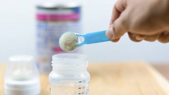 Baby formula being scooped into a bottle