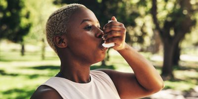 Woman using an inhaler outdoors.