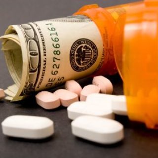 two prescription pill bottles on their side, one with pills spilling out and the other with rolled up hundred dollar bills