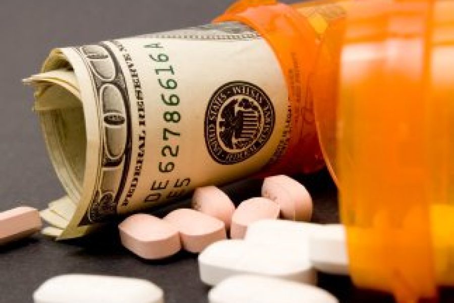 two prescription pill bottles on their side, one with pills spilling out and the other with rolled up hundred dollar bills
