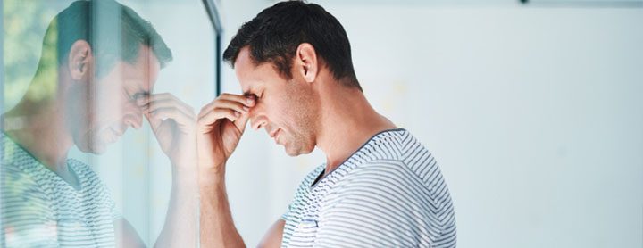 Man with a headache by a window