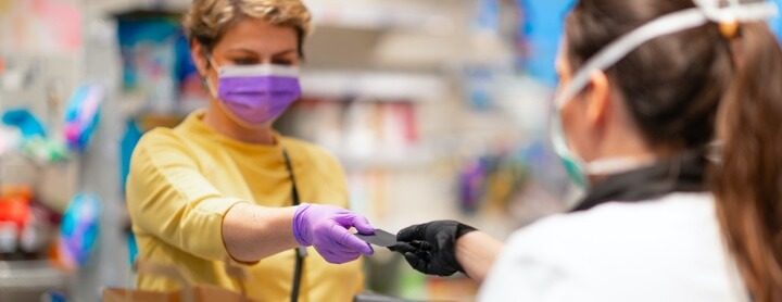 A woman wearing a face mask checks out at a pharmacy