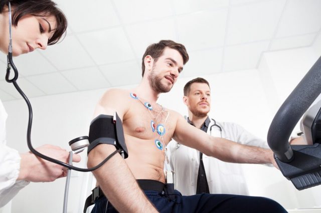 Doctors monitoring a male patient on exercise bike