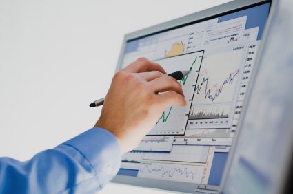 hand marking a chart on a computer screen