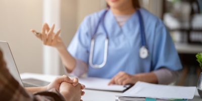 Close-up hand image of a serious patient having a medical consultation with a professional doctor at a hospital. Medical checkup, counseling, and diagnosis of disease