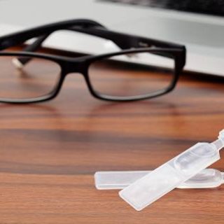 Dry eye drops, glasses and laptop