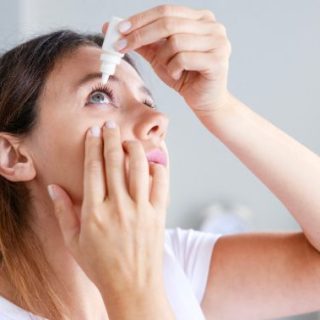 Woman putting eye drops in eye