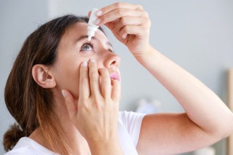 Woman putting eye drops in eye