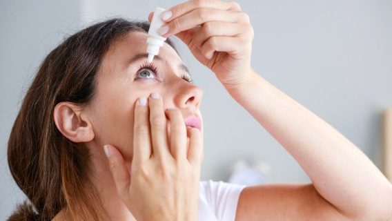 Woman putting eye drops in eye