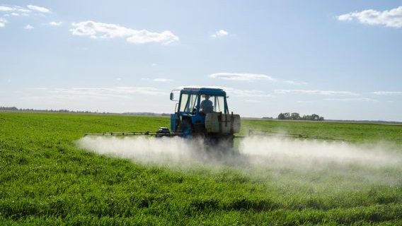 Farmer spraying weed killer with tractor