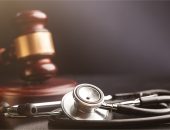 Stethoscope with a blurred wooden gavel with gold trim in the background.