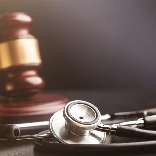 Stethoscope with a blurred wooden gavel with gold trim in the background.