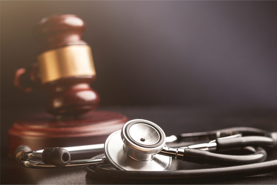 Stethoscope with a blurred wooden gavel with gold trim in the background.